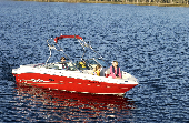 Mom, dad and kids on an anchored powerboat in the middle of the water.
