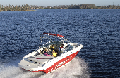 Mom, dad and kids riding in a powerboat with trees, houses and the shoreline in the background