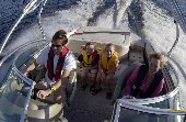 Adult male and female (mom and dad) wearing inflatable life jackets and kids wearing children's life jackets on a motor boat.