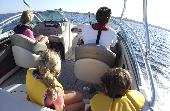 Shot taken from behind of an adult male and female, a boy and girl on a motor boat.