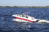 Adult male (dad), adult female (mom) and  two children sitting in the bow of a motor boat. The background is trees and houses.