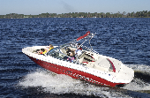 Adult male (dad), adult female (mom) and two children (boy and girl) sitting in the bow of a motor boat. Trees and houses are in the background.