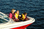 Adult female, wearing an inflatable life jacket, and a boy and girl wearing children's life jackets sitting in the bow.