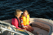 Adult female wearing an inflatable life jacket and girl in a children's life jacket sitting in the bow.