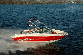 Adult male and female along with boy and girl in a moving motor boat with the shoreline in the background.