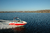 Adult male and female along with boy and girl in a moving motor boat with the shoreline in the background.
